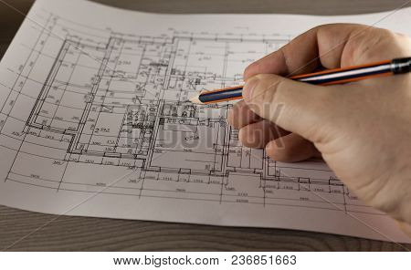 Hand With Pencil On Plan Of The House. Finance And Growth Of Business