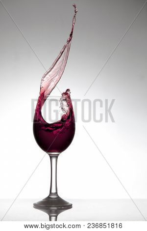Glass Of Red Wine, With Wine Splashing Out Of The Glass, On White Background
