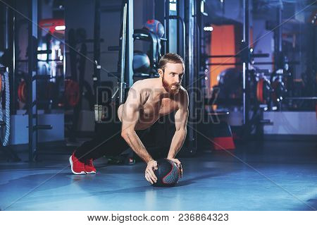Muscular Beards Man Doing Intense Core Workout In Gym. Doing Core Exercise On Fitness Mat With Medic
