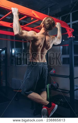 Black And White Image Of Power Muscular Bodybuilder Guy Doing Pullups In Gym. Fitness Man Pumping Up
