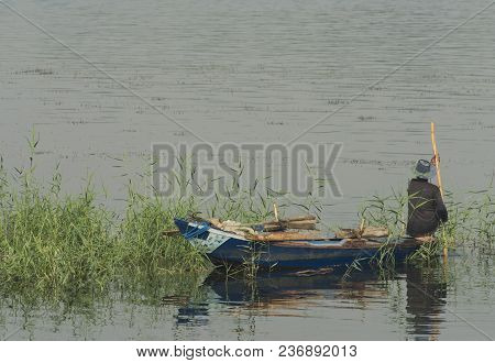Traditional Egyptian Bedouin Fisherman In Rowing Boat On River Nile Fishing By Riverbank Grass Reeds