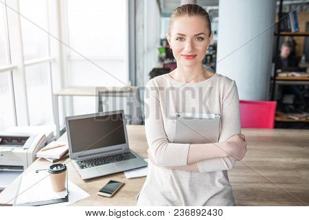 Portrait Of Happy, Good-looking And Confident Woman Sitting T The Adge Of The Table And Looking To T