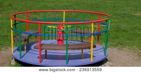 Children's Iron Carousel. Children's Playground. Swing, Carousel And Slide