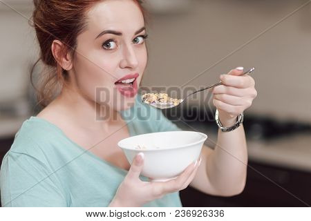 Beautiful Pregnant Woman Eating With Lust Cereals On Breakfast, Enjoying Meal. Yummy Food For Pregna