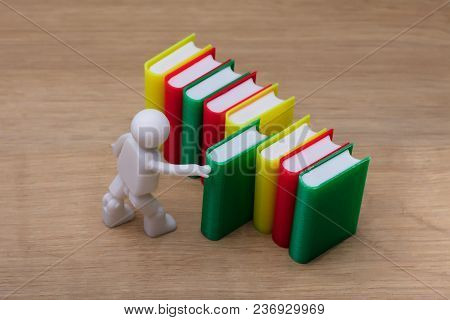 Elevated View Of Human Figure Selecting Green Book On Wooden Background