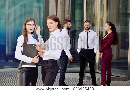 Business Lady. Office Staff. Two Young Girls With Electronic Tablets Communicate Against The Backgro