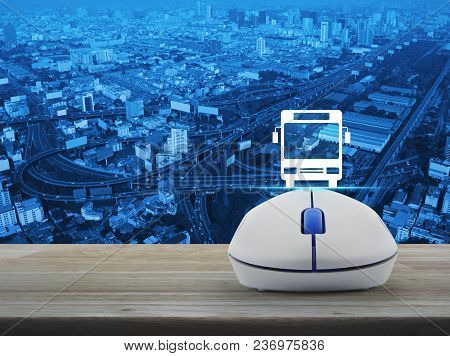 Bus Flat Icon With Wireless Computer Mouse On Wooden Table Over Modern City Tower, Street And Expres