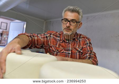 Cheese maker checking production in cheese cellar