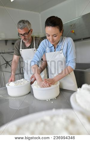 Couple of cheese makers molding sheep milk cheese
