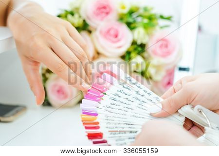 Woman during manicure choosing a nail color from many