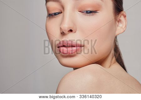 Young Beautiful Tender Pritty Girl With Blue Eyes And Full Lips. Grey Background. Dark Hair. Looking