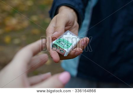 Kharkov, Ukraine - October 26, 2019: Young Man Takes Tic Tac Package To Girl In Autumn Park. Tic Tac
