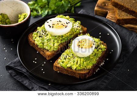 Avocado Sandwiches With Boiled Egg And Cereal Bread In Black Plate.