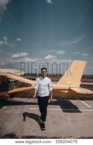 A Man Standing On The Background Of A Small Single Engine Plane.