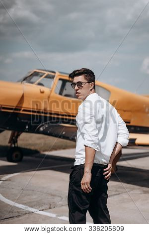 A Man Standing On The Background Of A Small Single Engine Plane.
