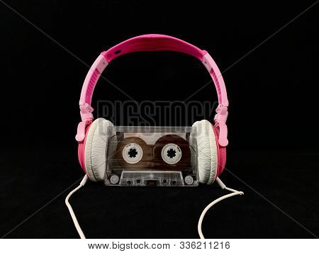 Plastic Cassette And Audio Headphones. Music Cassette On A Black Background. Concept: Music, Meloman
