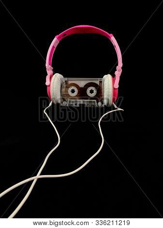 Plastic Cassette And Audio Headphones. Music Cassette On A Black Background. Concept: Music, Meloman