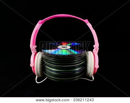 Stack Of Cds And Audio Headphones. Music Discs On A Black Background. Concept: Melomania.