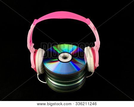Stack Of Cds And Audio Headphones. Music Discs On A Black Background. Concept: Melomania.