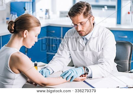 Selective Focus Of Handsome Allergist Holding Ruler Near Marked Hand Of Woman