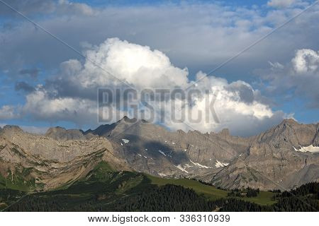 An Alpine Landscape With Mountains And Clouds In Summer