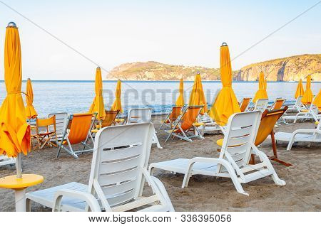 White Plastic And Metal Construction With Yellow Fabric Deckchairs Together With Yellow Umbrellas On