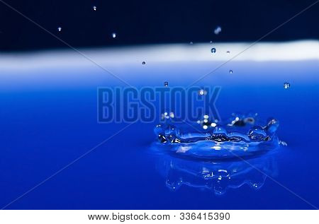 Falling Water Drop On Blue Background With Splashes