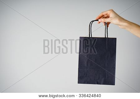 Paper Blue Craft Bag, Eco Packaging In A Female Hand, On A Gray Background, With Place For Text. Sal
