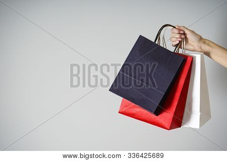 Colored Paper, Kraft Eco Packs On A Gray Background In A Female Hand, With Room For Text. Sale & Bla
