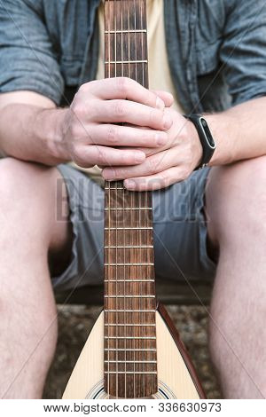Mens Hands Hold An Acoustic Guitar For Traveling Behind A Griff Or Neck.