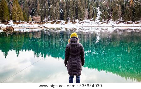 woman watchin amazing turquoise water of Caumasee in winter Switzerland slow travel