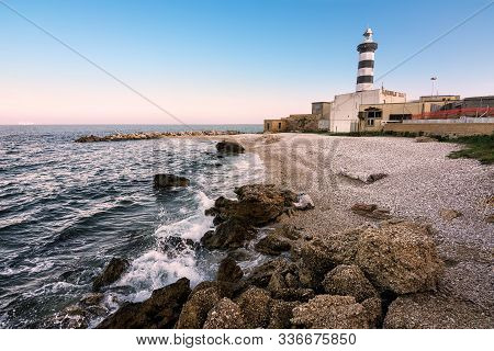 The Faro Di Ortona And Its Pebble Beach At Sunset