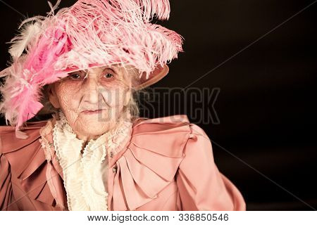 Old Stylish Lady In Mauve Jacket And A Hat