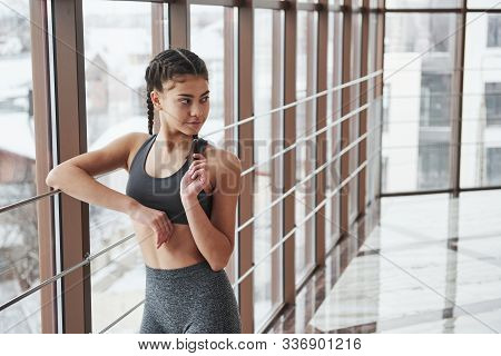Brunette Girl In Sportswear Posing And Laying On Railings Near Window In The Gym.