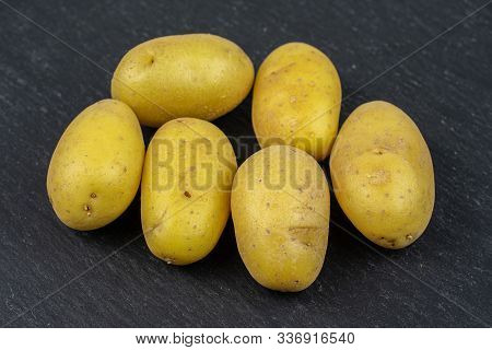 Group Of Six Whole Pale Yellow Potato On Grey Stone