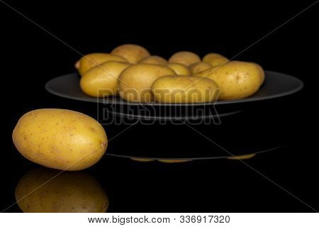 Lot Of Whole Pale Yellow Potato On Gray Ceramic Plate Isolated On Black Glass