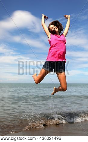 Young Smiling Girl Taking A Super High Jump For Joy Happiness Over The Calm Sea