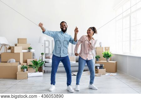 Satisfies Excited Young African American Lady And Guy Dancing In Living Room With Cardboard Boxes Wi