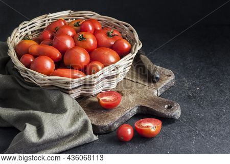 Fresh Red Tomatoes In Whicker Basket On Black Background.