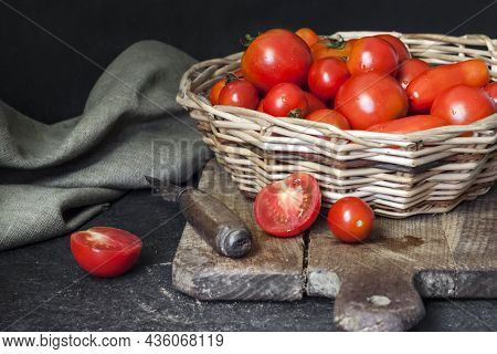 Fresh Red Tomatoes In Whicker Basket On Black Background.