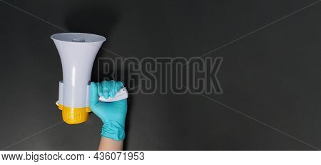 Megaphone In Hand And Wearing Blue Latex Glove On Black Background. Studio Shooting.