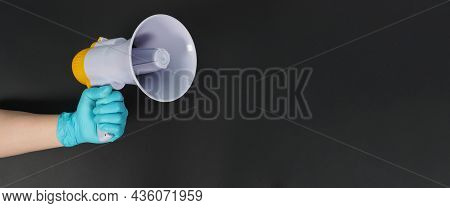Megaphone In Hand And Wearing Blue Latex Glove On Black Background. Studio Shooting.
