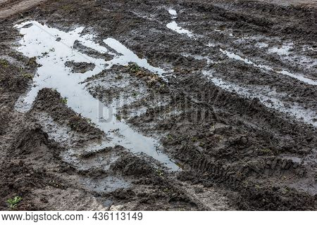 A Broken Rural Country Road. Puddles After Rain On A Dirt Road. Clay, Soil And Puddles At Cloudy Day