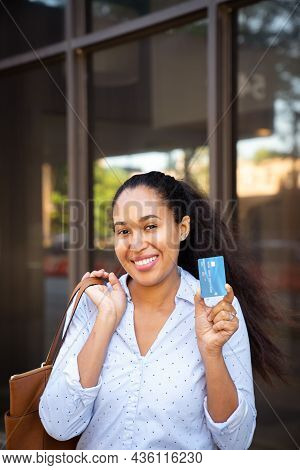 A Beautiful Mixed Race African American Woman In A Blue Collared Shirt Holds Up A Blue Plastic Credi