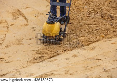 Worker In Use Vibratory Plate Compactor For Path Construction. Plate Compactor For Compaction Sand. 