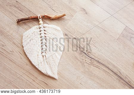 Macrame Leaf  In Natural Color And Thread Windings Lying On A Wooden Table. Cotton Rope Decor Macram