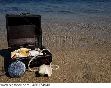 A Pirate Treasure Chest On A Sandy Beach.a Treasure Trove Of Seashells, Antique Watches And Jewelry 