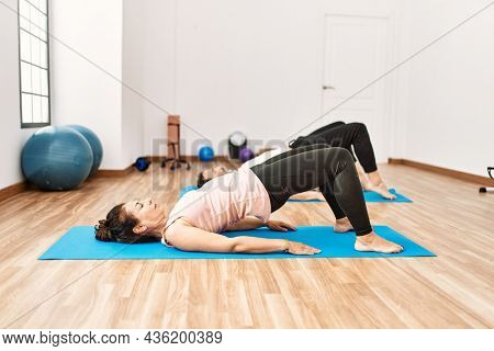 Mature hispanic couple doing excersice and stretching at yoga room. Two adult people doing pilates and flexibility workout
