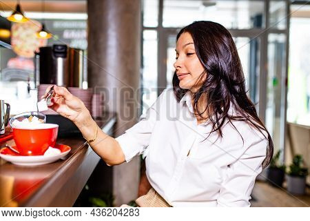 Indian Reading Notes In Notepad While Sitting Near Table Bar And Drinling Cup Of Tea