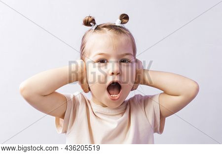 Cute Naughty Little Girl Covered Her Ears With Both Hands And Screams. The Tense Little Girl Covered